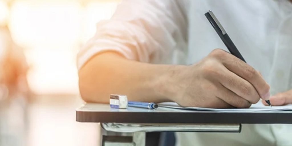 A hand writing with a pen and there is pencil and rubber on the table